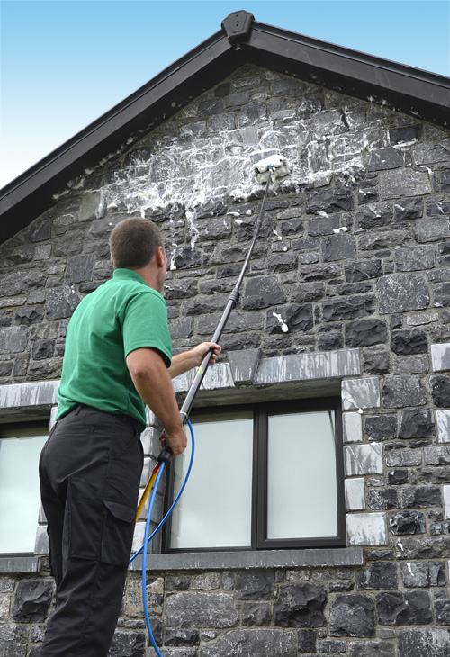 Cleaning natural stone wall with OutCide's high reach pole system.